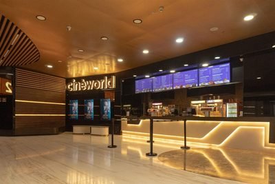 Cinèworld lobby with glowing sign, film posters and a lit food counter with menu screens