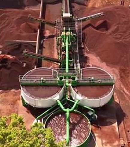 Aerial view of iron ore beneficiation thickener tanks among red ore